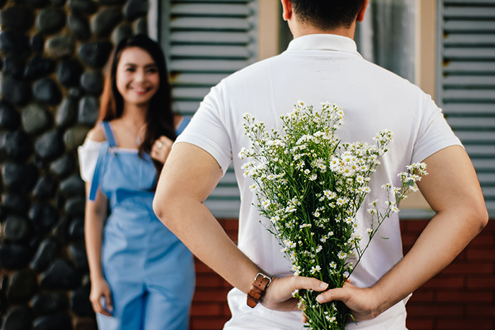 Mann versteckt hinter seinem Rücken Blumen für sein Date